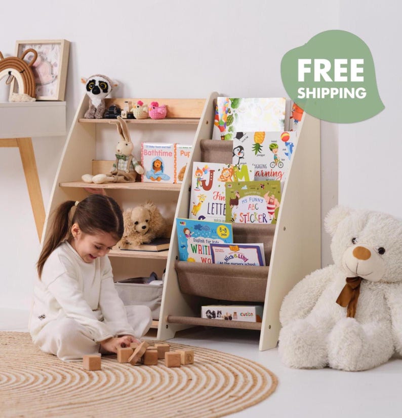 May include: A white and wood-toned bookshelf with multiple shelves, filled with children's books and stuffed animals. A young child is playing with wooden blocks on a round rug. The bookshelf has a unique angled design.