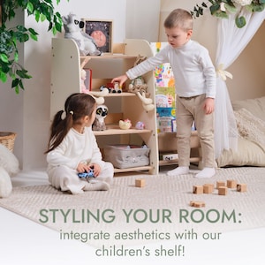May include: A light-colored wooden children's bookshelf with multiple shelves, filled with toys and books. Two children are interacting with the shelf. The text "STYLING YOUR ROOM: integrate aesthetics with our children's shelf!" is at the bottom.