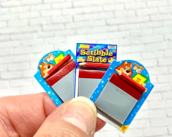 May include: Three miniature red and gray dry erase boards with a blue and white border. The boards have a cartoon squirrel on the front and the words "Neon Scribble Slate" on the packaging.