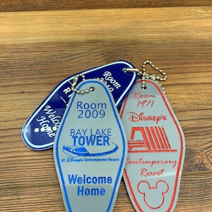 May include: Three vintage hotel keychains with blue, gray, and red colors. The keychains feature the text "Room 2010", "Room 2009 Bay Lake Tower at Disney's Contemporary Resort Welcome Home", and "Room 1971 Disney's Contemporary Resort".