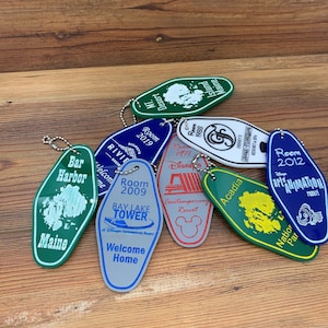 May include: A collection of colorful keychains featuring various Disney resort hotels, including the Contemporary Resort, Bay Lake Tower, and Animal Kingdom Lodge. Each keychain is shaped like a hotel room key and features the hotel's name and logo.