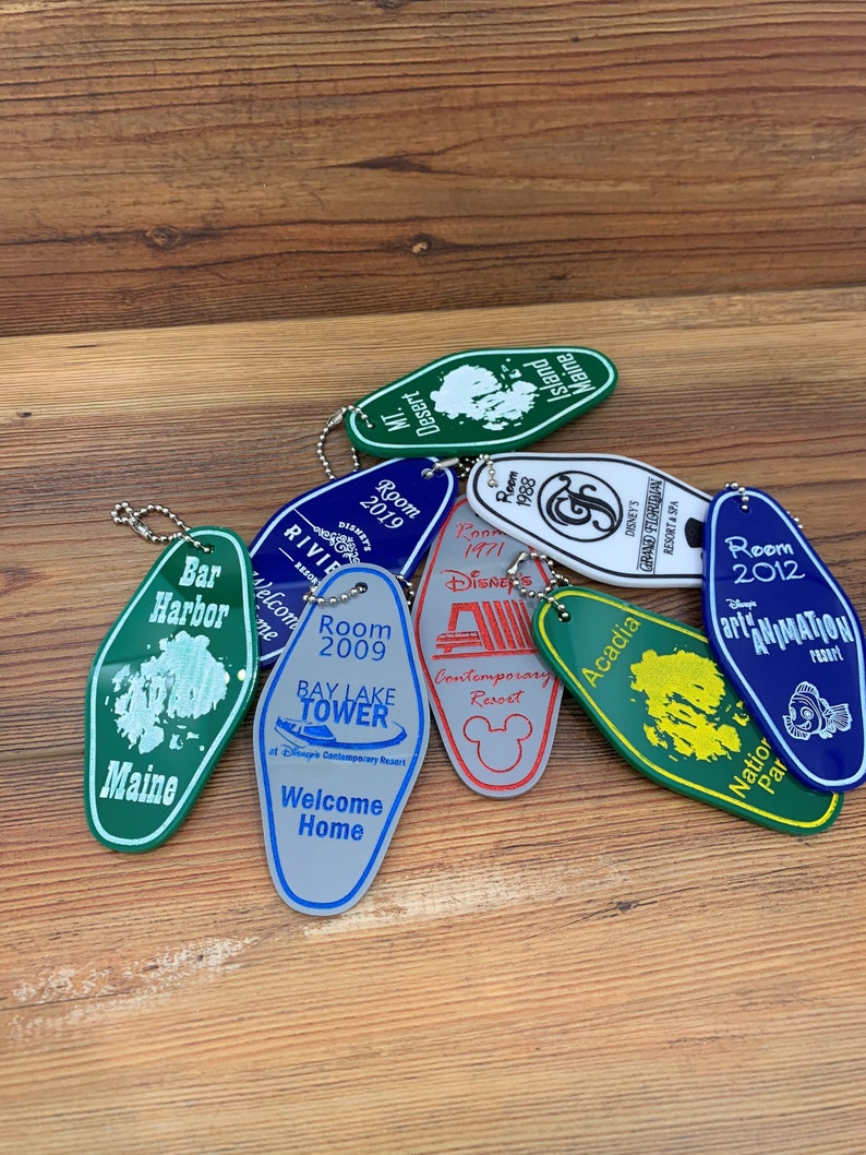 May include: A collection of colorful keychains featuring various Disney resort hotels, including the Contemporary Resort, Bay Lake Tower, and Animal Kingdom Lodge. Each keychain is shaped like a hotel room key and features the hotel's name and logo.