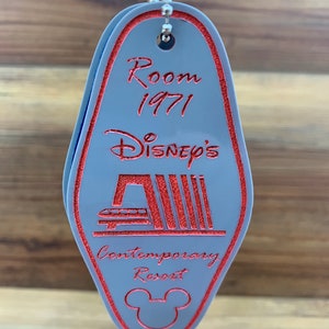 May include: A gray plastic hotel key chain with red text and a red Mickey Mouse silhouette. The text reads "Room 1971 Disney's Contemporary Resort".