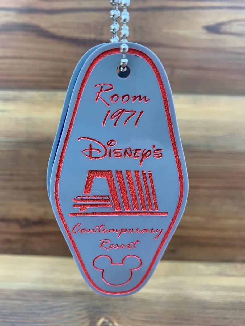 May include: A gray plastic hotel key chain with red text and a red Mickey Mouse silhouette. The text reads "Room 1971 Disney's Contemporary Resort".