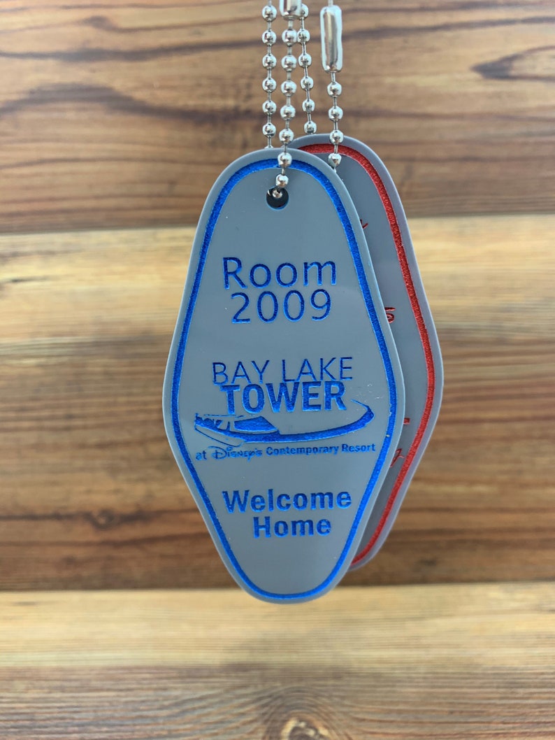 May include: A gray key chain with a blue and white hotel key tag. The key tag has the text "Room 2009", "Bay Lake Tower", "at Disney's Contemporary Resort", and "Welcome Home".