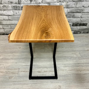 May include: A wooden table with a live edge top and a black metal base. The table is made of natural wood and has a rustic look.
