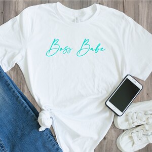 May include: White t-shirt with the text "Boss Babe" in teal blue script.