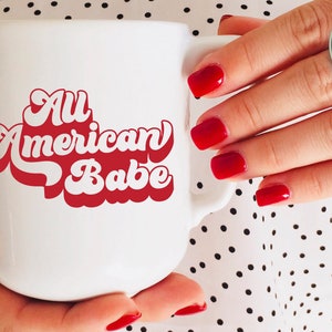 May include: White ceramic mug with a red retro-style graphic that says "All American Babe".