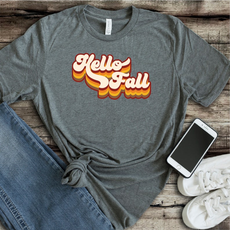 May include: A grey t-shirt with the text "Hello Fall" in a retro, multi-coloured font.