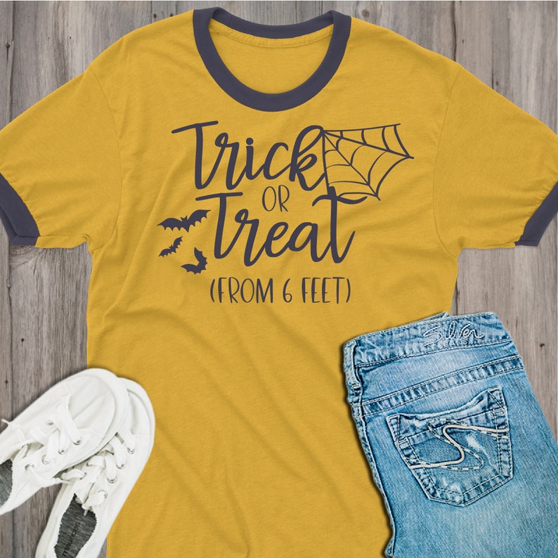 May include: A yellow t-shirt with a black ringer and the text "Trick or Treat (From 6 Feet)" in black. The shirt has a spiderweb graphic and three bats.