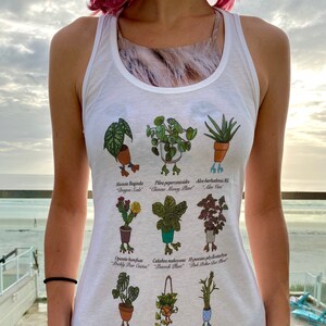 Puede incluir: Camiseta sin mangas blanca con una ilustración botánica de varias plantas en macetas, cada una etiquetada con sus nombres científicos y comunes. Las plantas incluyen aloe vera, escama de dragón y bambú de la suerte. El diseño es de estilo caricatura.