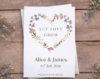 Peut inclure: Un sachet en papier rectangulaire blanc orné d'une couronne en forme de cœur composée de fleurs sauvages pressées colorées. Le texte LET LOVE GROW, Alice & James, 11th July 2026 et WILDFLOWER SEEDS est imprimé en gris foncé au centre.