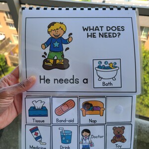 May include: An educational book for children with the text "WHAT DOES HE NEED?" and "He needs a". The book features illustrations of a boy in mud, a bath, tissue, band-aid, nap, medicine, drink, doctor, and a toy.