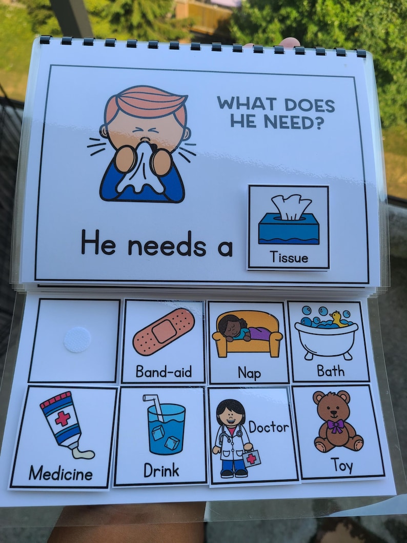 May include: A learning aid book titled "WHAT DOES HE NEED?" with illustrations of a person sneezing, a tissue box, a plaster, a nap, a bath, medicine, a drink, a doctor, and a toy.