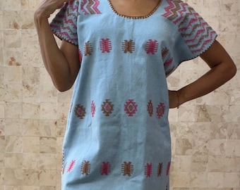 May include: A light blue embroidered dress with pink and brown geometric patterns. The dress has short sleeves and a scoop neck.