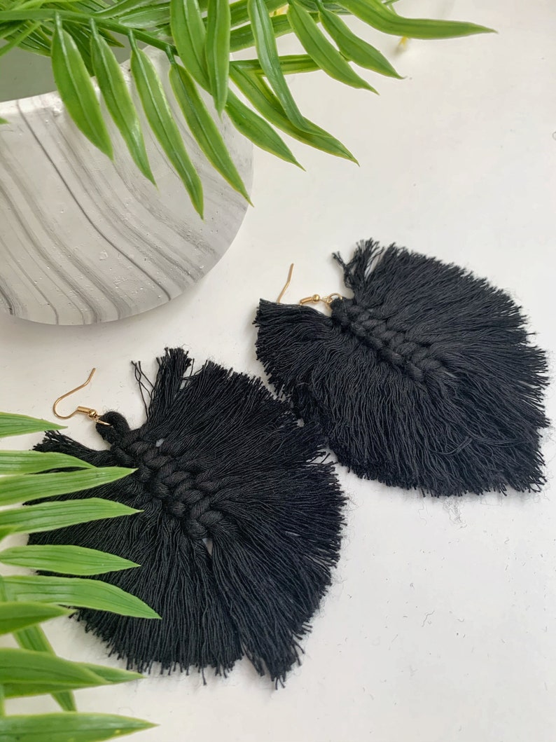 Puede incluir: Un par de pendientes de borla negros con ganchos dorados. Las borlas est&aacute;n hechas de un material suave y tejido y miden aproximadamente 7,5 cm de largo.
