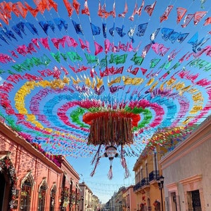 May include: A colorful display of paper flags hanging from a ceiling, creating a festive atmosphere. The flags are in various shades of red, yellow, blue, green, and purple, forming a circular pattern. The flags are strung together with string and are hanging from a ceiling.