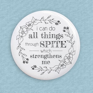 Może przedstawiać: Biały, okrągły guzik z czarną ramką w postaci wieńca kwiatowego. Tekst wewnątrz wieńca brzmi "i can do all things through SPITE which strengthens me".