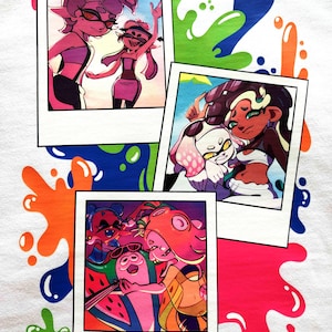 Puede incluir: Una superficie de tela blanca con tres fotograf&iacute;as impresas estilo polaroid de personajes de dibujos animados. El fondo est&aacute; decorado con salpicaduras de pintura vibrantes y multicolores en verde, azul, naranja y rosa.