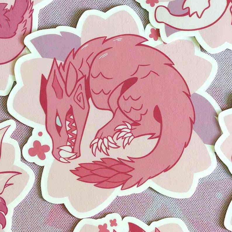 May include: Pink sticker featuring a stylized dragon illustration. The dragon is curled up, with sharp claws, teeth, and a spiky mane. The sticker is on a light pink floral background, with other similar stickers visible.