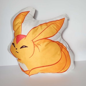 K&ouml;nnte beinhalten: Ein Pl&uuml;schkissen in Form eines gelben und orangefarbenen Fuchses mit einer roten Spitze am Ohr. Der Fuchs hat einen wei&szlig;en Bauch und einen wei&szlig;en Fleck auf der Brust.