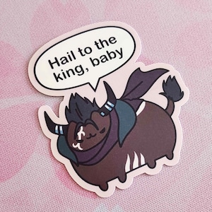 May include: A sticker featuring a cartoon yak-like creature with dark brown fur, a dark purple cape, and horns. The yak has a speech bubble that says "Hail to the king, baby". The sticker is on a pink background.