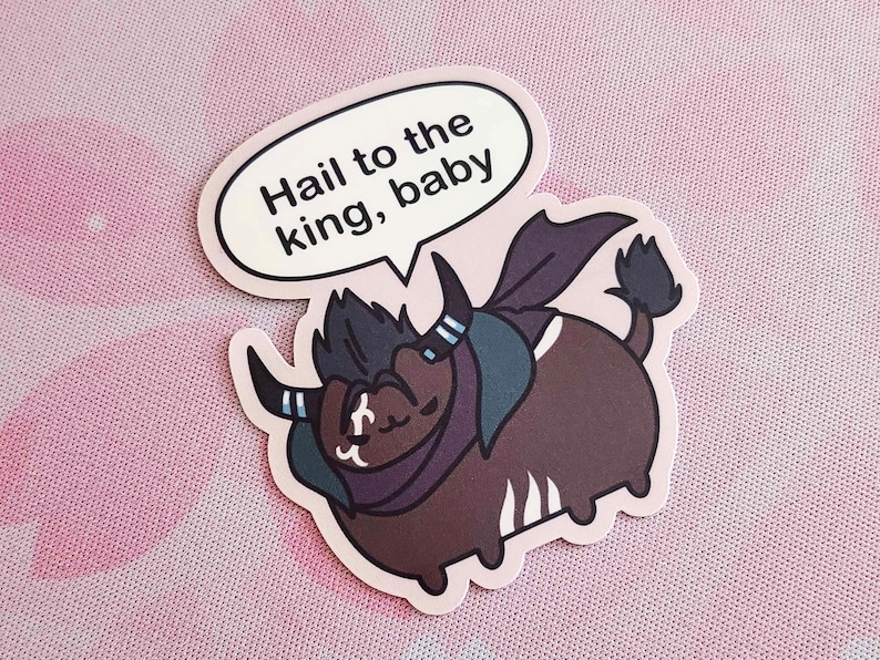 May include: A sticker featuring a cartoon yak-like creature with dark brown fur, a dark purple cape, and horns. The yak has a speech bubble that says "Hail to the king, baby". The sticker is on a pink background.
