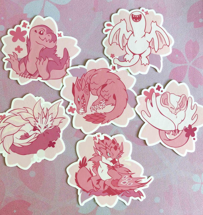 May include: A collection of six pink and white stickers featuring cartoon monster illustrations. Each sticker is shaped like a flower and has a different monster design, including dragons and other fantasy creatures. The stickers are in various shades of pink.