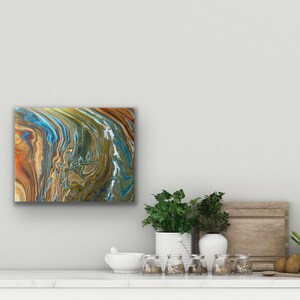 Puede incluir: Pintura abstracta con patrones en espiral en tonos marrones, azules y verdes. La pintura est&aacute; enmarcada y colgada en una pared blanca.
