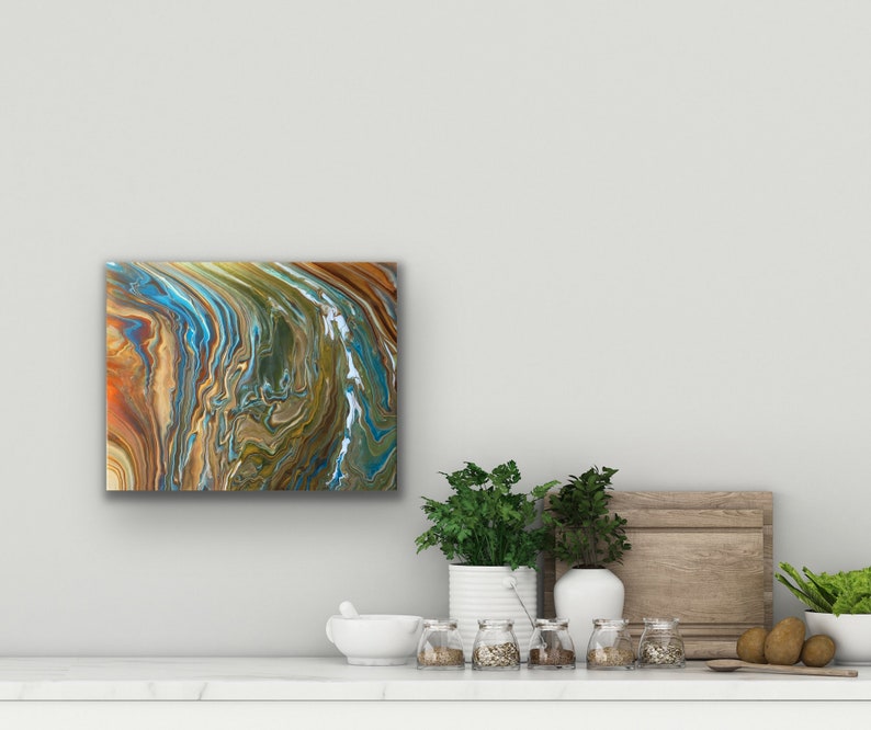 Puede incluir: Pintura abstracta con patrones en espiral en tonos marrones, azules y verdes. La pintura est&aacute; enmarcada y colgada en una pared blanca.