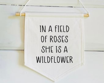 In een veld met rozen is She Is A Wildflower Banner - muurbanner kinderkamer - kinderbanner - kinderkamerdecoratie - babymeisje kinderkamer - Wild Child