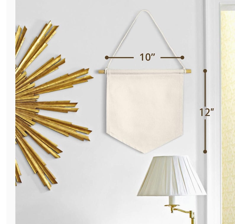 Op de afbeelding: Een blanco canvasbanner met een houten stok aan de bovenkant en een touw om op te hangen. De banner is 25,4 cm breed en 30,5 cm hoog.