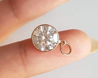 May include: A gold pendant featuring a large, round, clear cubic zirconia stone.