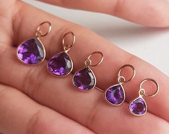 May include: Five gold charms with purple amethyst stones in different sizes. The charms are in the shape of teardrops.