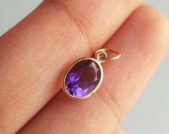 May include: A gold pendant with a purple oval amethyst gemstone.
