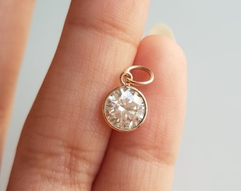 May include: A gold pendant with a round, clear, faceted gemstone.
