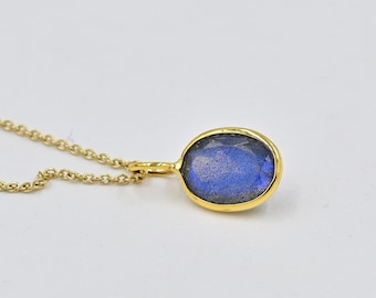 May include: A gold chain necklace with a pendant featuring a blue oval labradorite gemstone.