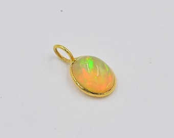 May include: A gold pendant featuring a white opal gemstone. The opal displays a green and orange iridescent sheen.