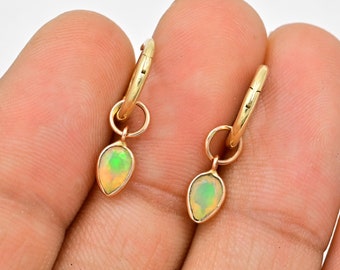May include: A pair of gold hoop earrings with a teardrop-shaped opal pendant hanging from each hoop.