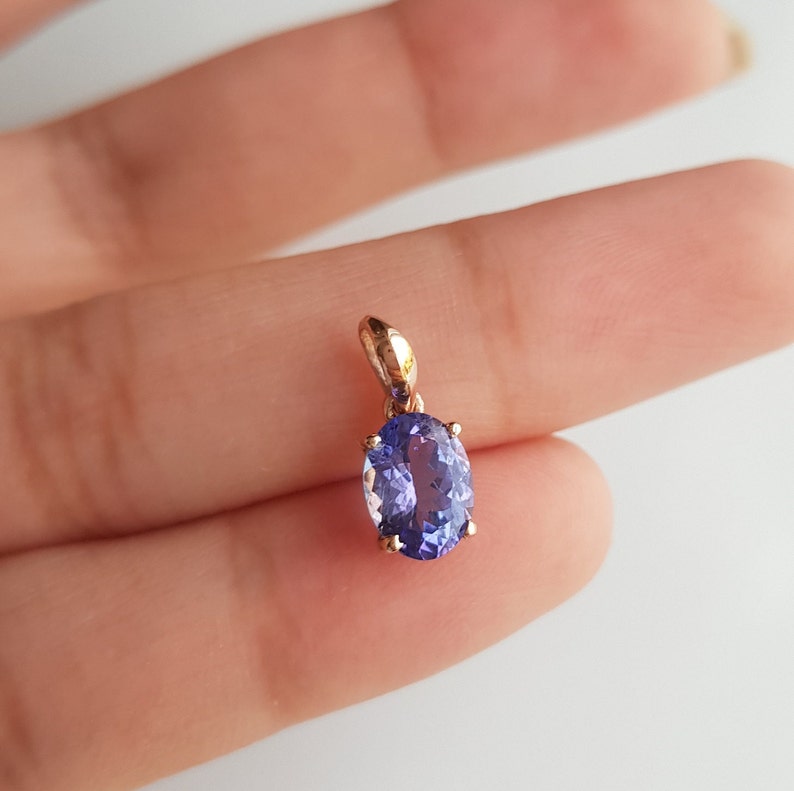 May include: A pendant featuring a large oval-shaped purple gemstone set in a gold setting.