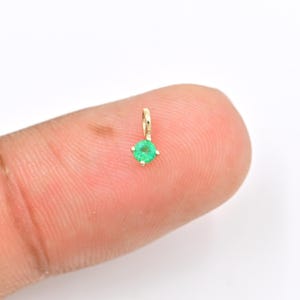 Puede incluir: Un pequeño colgante de oro con una esmeralda verde redonda.