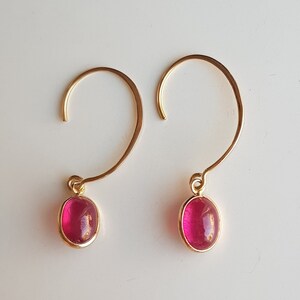 May include: A pair of gold earrings with pink oval-shaped gemstones.