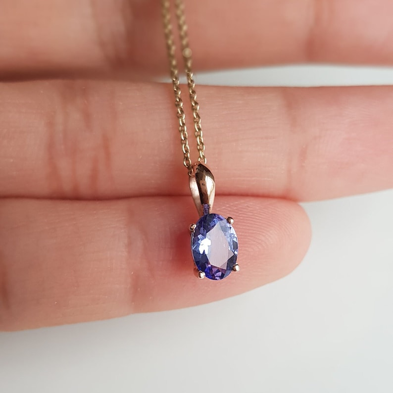 Op de afbeelding: Een gouden ketting met een hanger met een lichtpaarse ovale edelsteen.