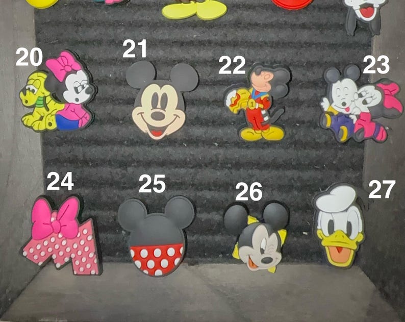 May include: A collection of colorful cartoon character charms, including Mickey Mouse, Minnie Mouse, and Donald Duck. The charms feature various designs and colors, perfect for personalizing accessories.