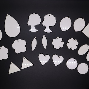 May include: A collection of white ceramic blanks in various shapes, including hearts, leaves, paw prints, and squares. The blanks have a smooth, matte finish and are ready to be painted or decorated.