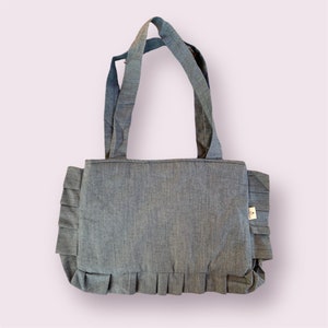 Op de afbeelding: Een blauwe denim tote bag met een gerimpelde rand en twee bovenste handvatten.