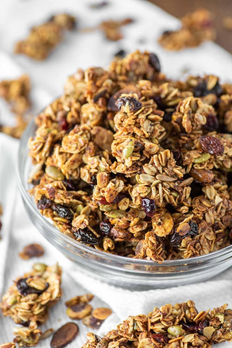 May include: A glass bowl filled with homemade granola. The granola is made with oats, nuts, seeds, and dried fruit. It is a healthy and delicious breakfast or snack option.