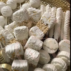 May include: A platter of white chocolate treats, including cake pops, rice krispie treats, and chocolate-covered pretzels, all decorated with gold sprinkles.