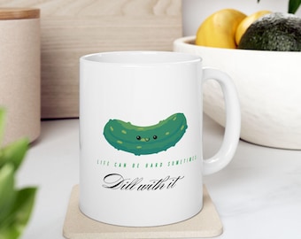 Op de afbeelding: Witte keramische mok met een groene augurkenillustratie en de tekst "Het leven kan soms moeilijk zijn. Dill with it."