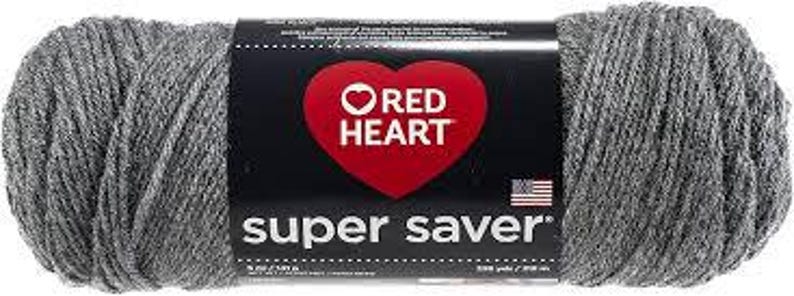 May include: A skein of heather grey yarn wrapped in a black paper label featuring a red heart logo, the text Red Heart Super Saver, and a small American flag. The label indicates a weight of 5 ounces or 141 grams and a length of 236 yards or 215 meters.